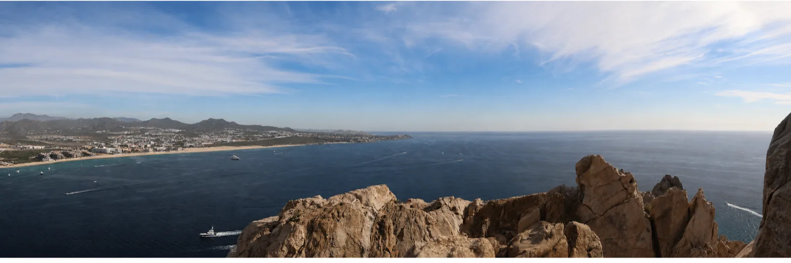 A panoramic view over the coast and deep blue water from a rocky overlook.