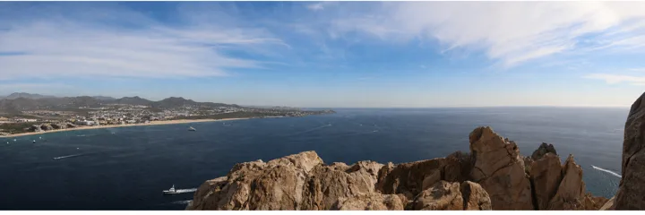 A panoramic view over the coast and deep blue water from a rocky overlook.